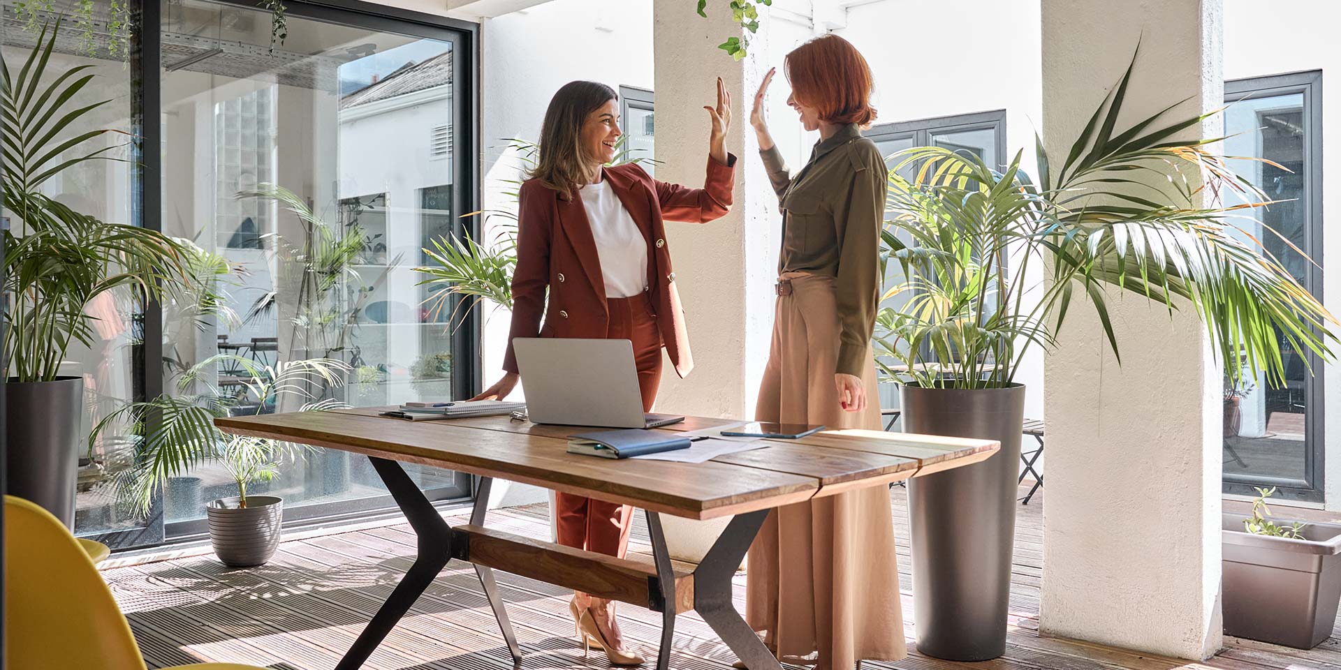 Zwei Mitarbeiterinnen freuen sich über einen beruflichen Erfolg in einem Green Office. © Adobe Stock, insta_photos