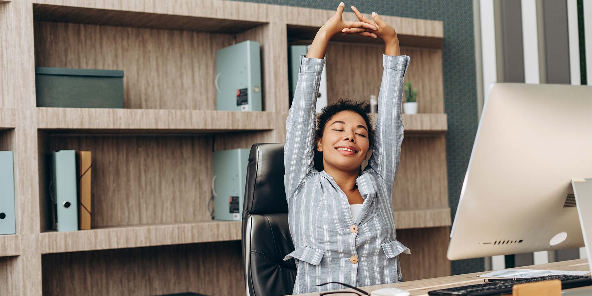 Mitarbeiterin dehnt sich an ihrem Bildschirmarbeitsplatz. © Adobe Stock, Maria Vitkovska