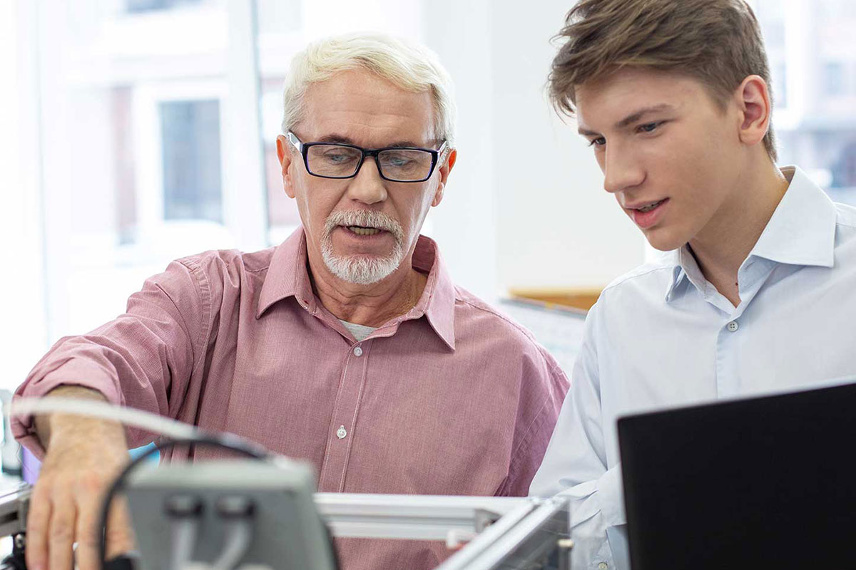 Mitarbeiter arbeitet einen Azubi im Rahmen seiner betrieblichen Ausbildung an technischen Geräten ein. © Adobe Stock, zinkevych
