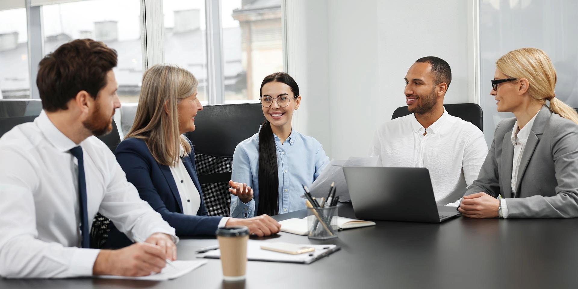 Ein altersgemischtes Team, mit älteren und jüngeren Mitarbeitenden, sitzt im Büro an einem Tisch und hält ein Meeting ab. © Adobe Stock, New Africa