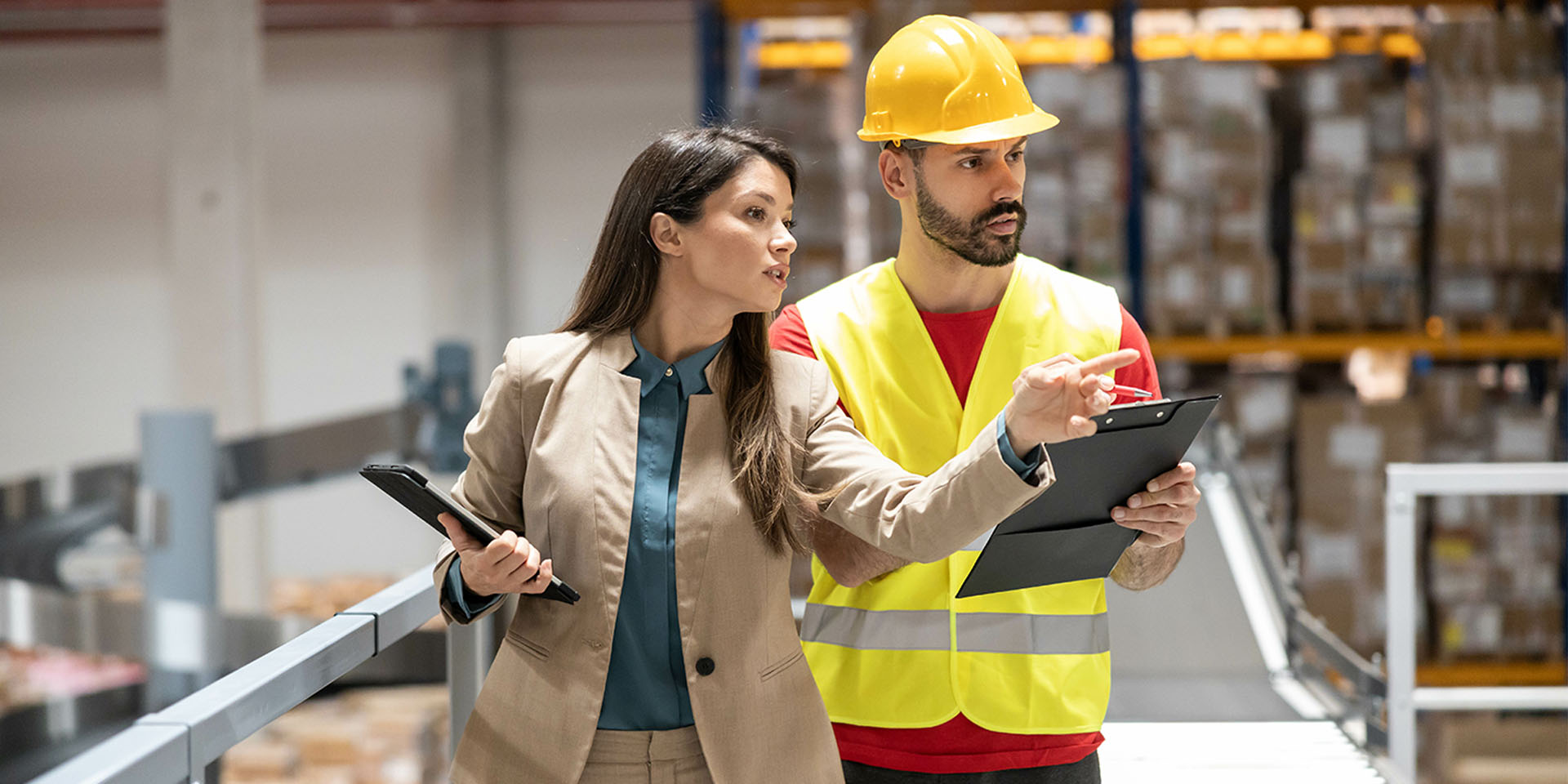 Sicherheitsbeauftragte der betriebsärztlichen und sicherheitstechnischen Betreuung im Gespräch mit Mitarbeiter im Lager, beide mit Klemmbrettern. © Adobe Stock, Dejan