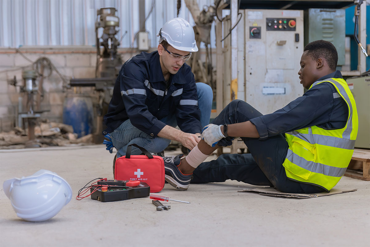 Erste Hilfe bei Fußverletzung in Werkhalle als Teil der betriebsärztlichen und sicherheitstechnischen Betreuung. © Adobe Stock, Kanpisut