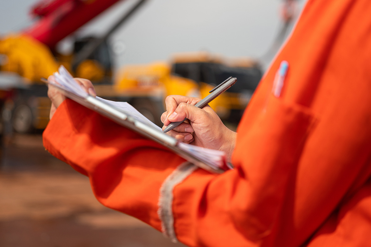 Mitarbeiter in Sicherheitskleidung füllt den Erfassungsbogen Arbeitsschutz aus.