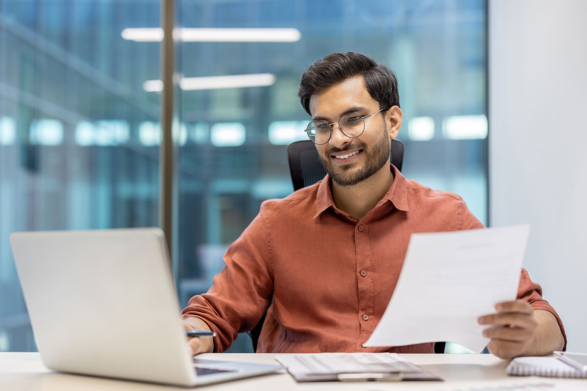 Mitarbeiter freut sich über seinen Bonus und arbeitet motiviert an seinem Laptop.